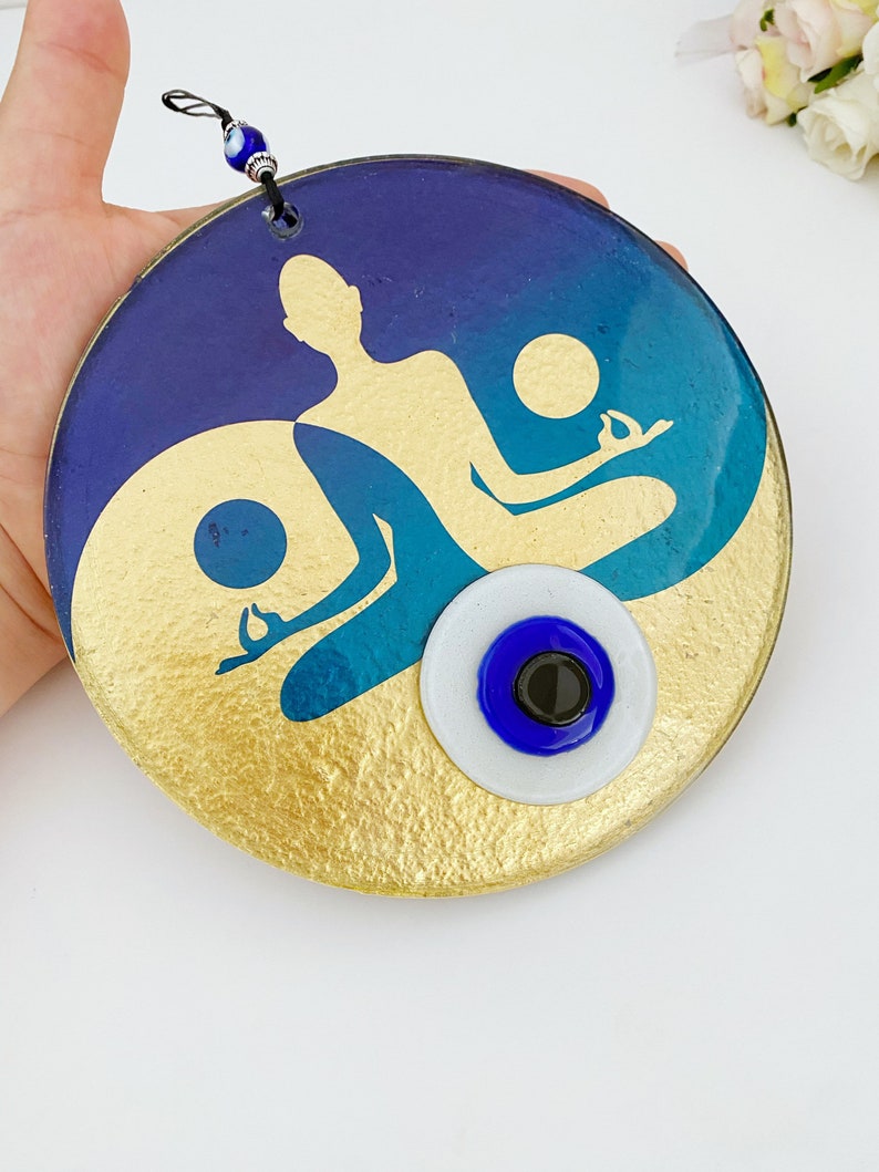 Pendentif mural rond en bleu et or avec silhouette yoga et œil protecteur