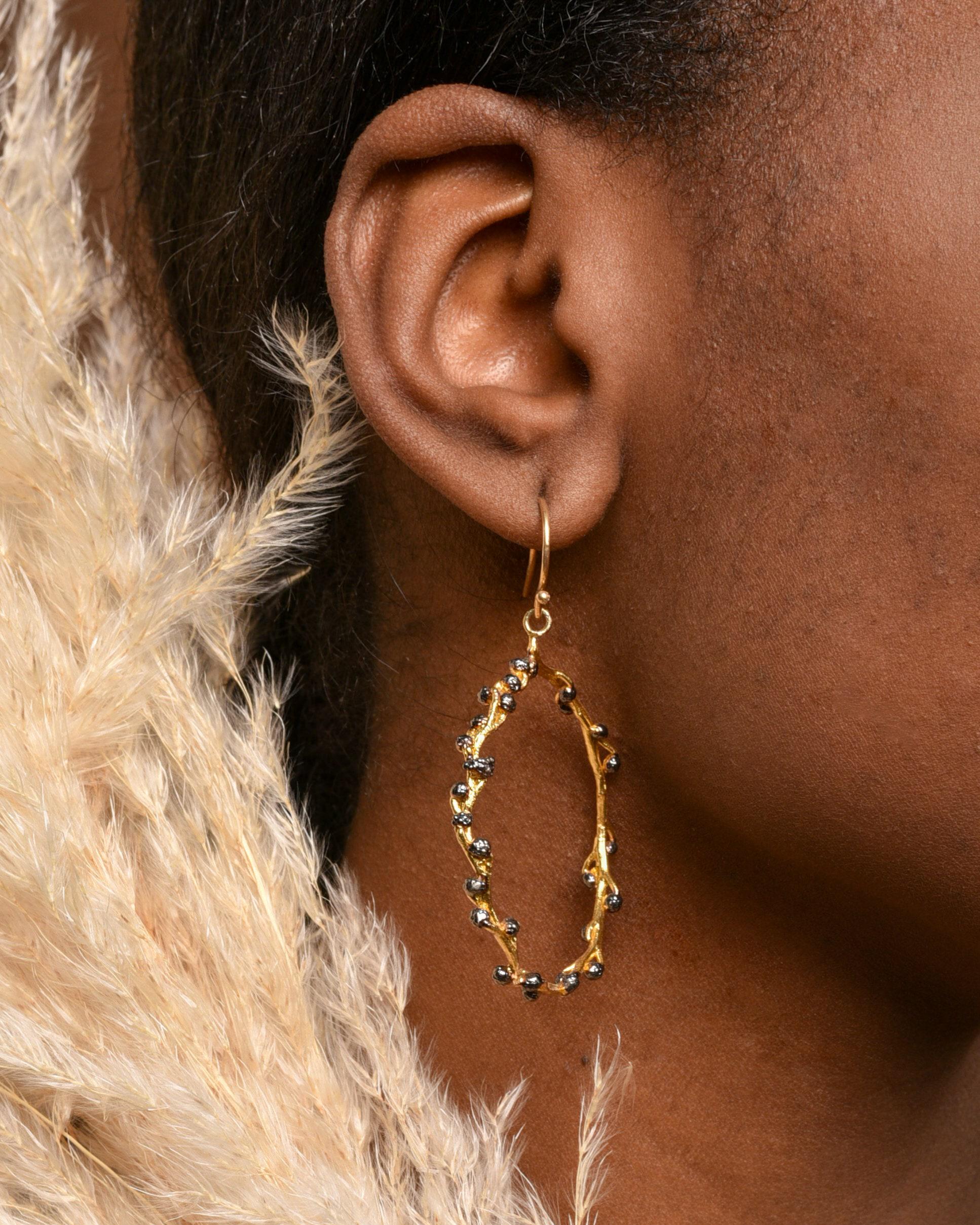 Boucle d’oreille créole dorée, branchage ajouré, petites billes bleues et pampille