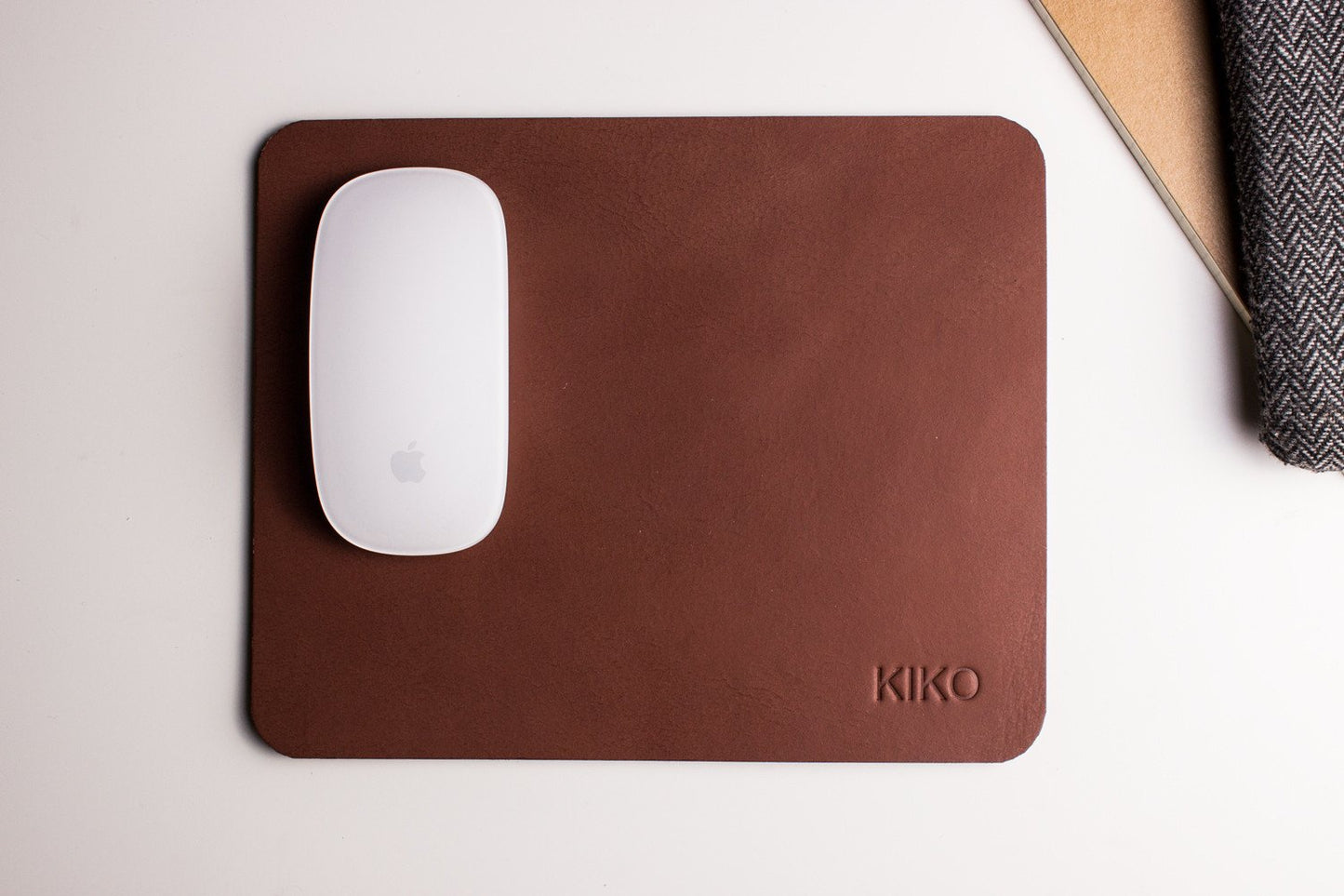 Tapis de souris en cuir brun avec souris blanche, logo KIKO en bas à droite.
