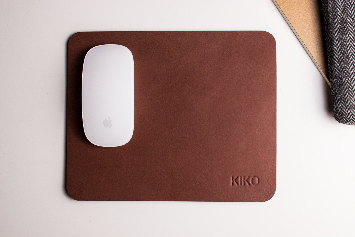 Tapis de souris en cuir brun avec souris blanche, logo KIKO en bas à droite.