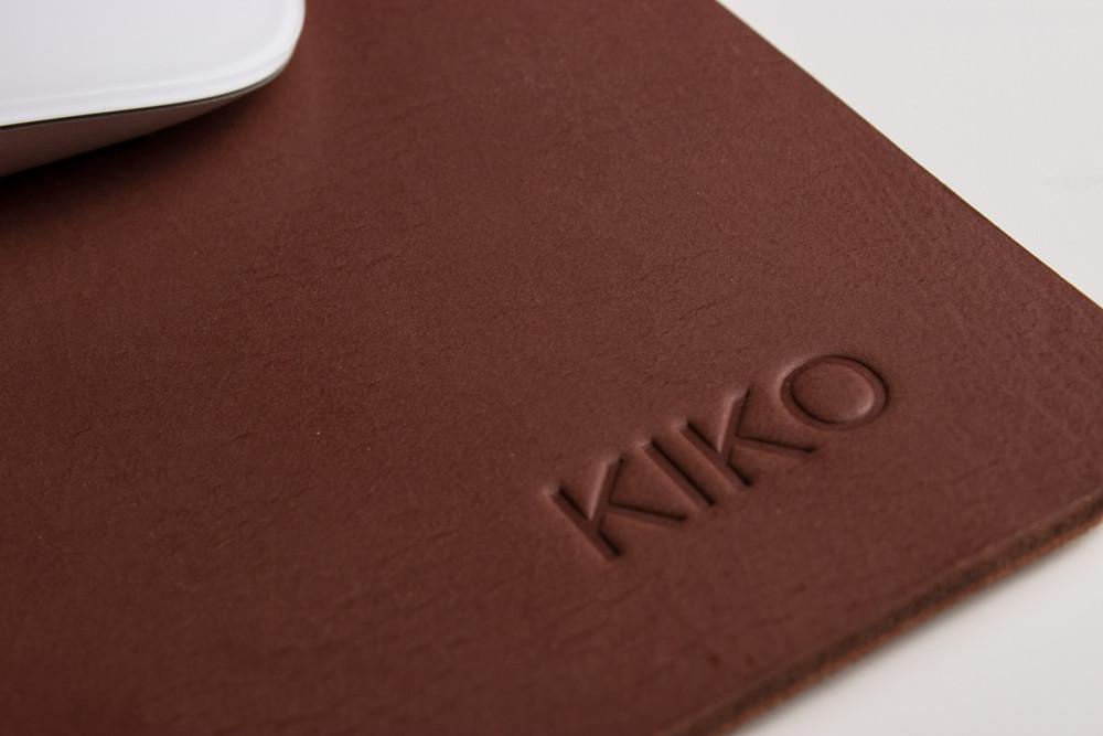 Détail du tapis de souris en cuir brun : logo KIKO embossé sur la surface.