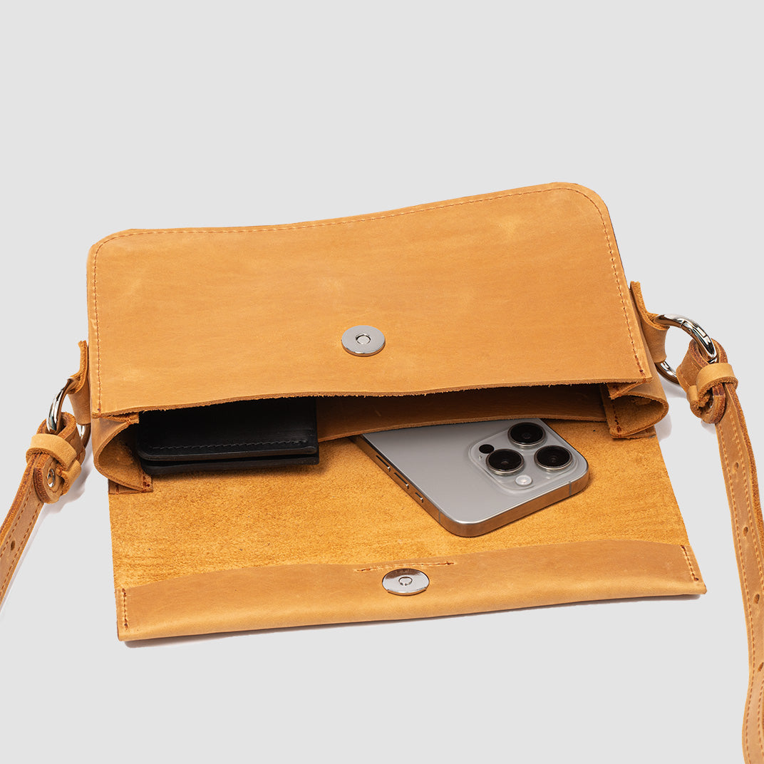 Sac bandoulière en cuir orange ouvert, rabat à boutons et poche intérieure pour téléphone.