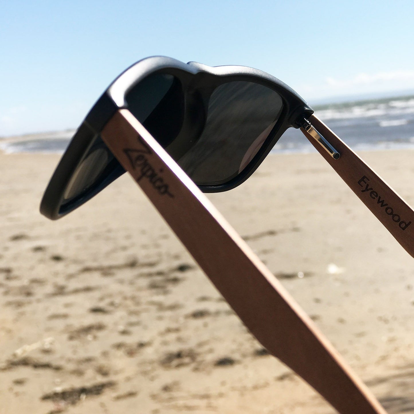 Lunettes de soleil monture noire, verres foncés et branches en bois brun, angle